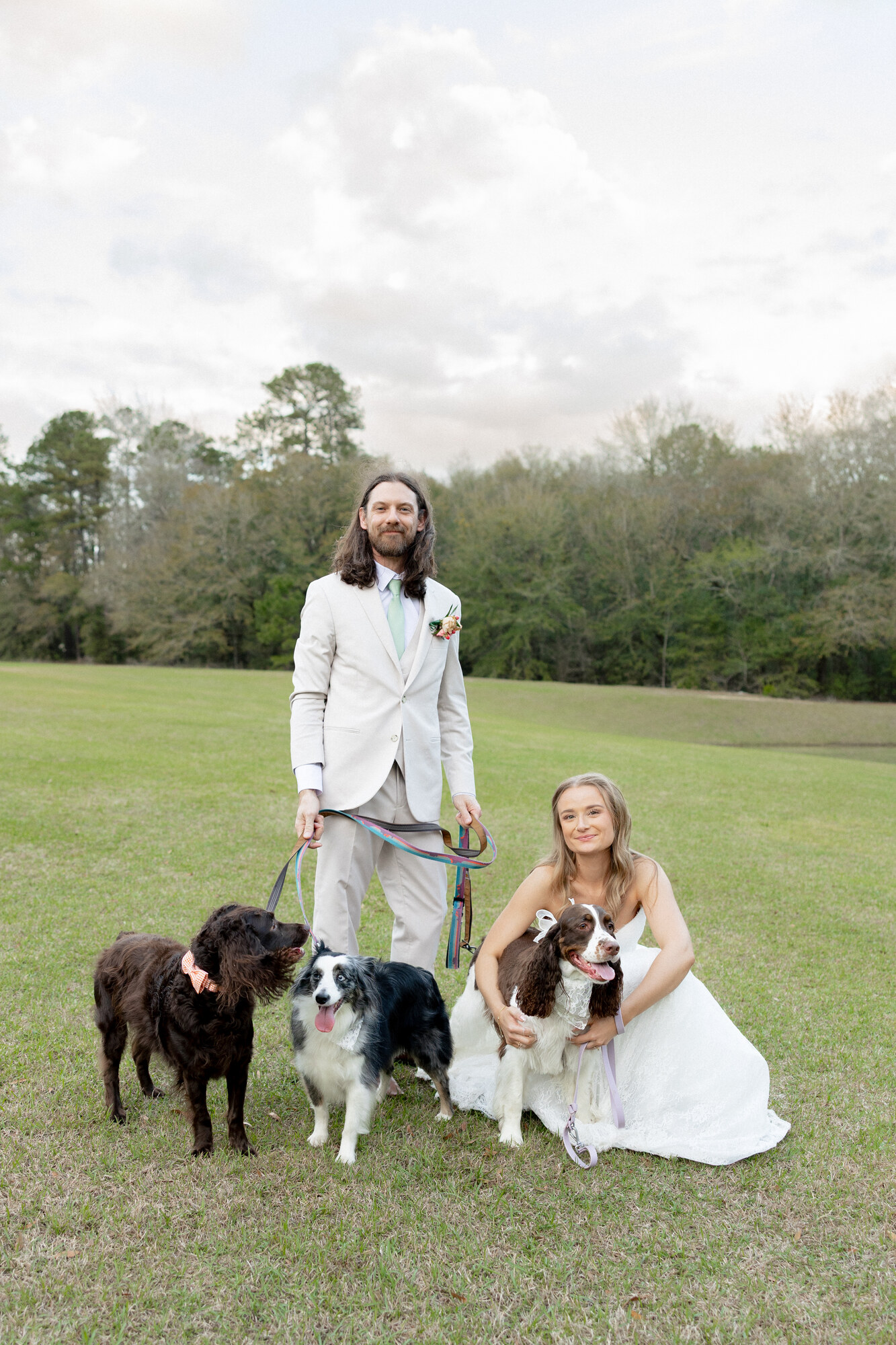 Bride and groom with their three dogs in the field at The Cabin at Old Spur
